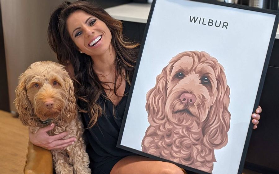 Een vrouw knuffelt haar labradoodle Wilbur naast zijn portret